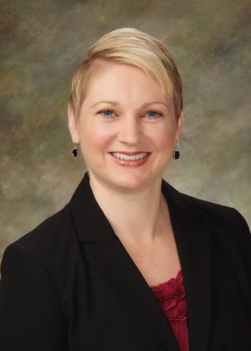 Alt text: Woman in a black blazer with a neutral background.